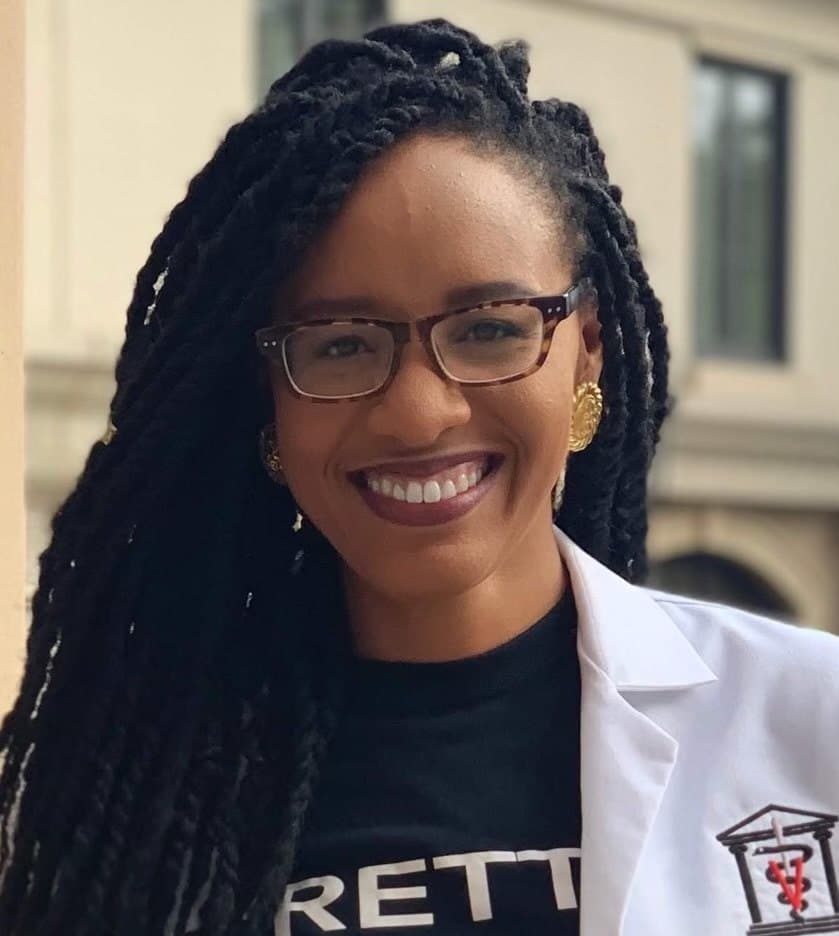 Dr. Aisha Ellis smiling outdoors in her white veterinary coat